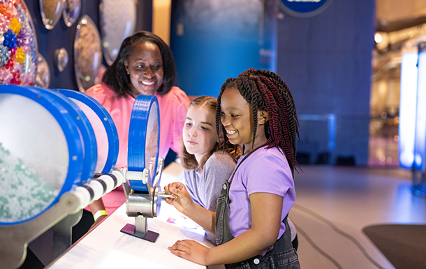 Adult and two girls looking at an exhibit